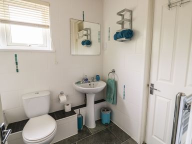 A bathroom with a toilet sink mirror towel rack and window at Hillside in Gunnislake