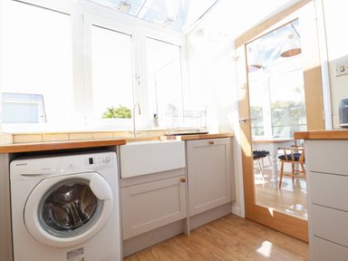 A kitchen with a washing machine a sink and wooden countertops at Seawynds in Crantock