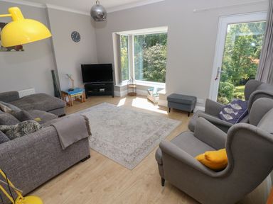 A living room with gray sofas a television and a large window at Pinewood in Saundersfoot