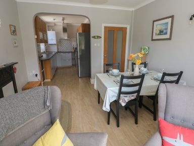 A dining area with a set table and a kitchen in the background at Pinewood in Saundersfoot