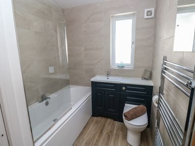 A bathroom with a bathtub sink toilet and towel rail at Pinewood in Saundersfoot