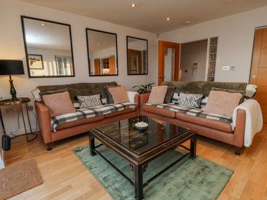 A living room with two brown sofas and a black coffee table on a green rug at A Stone's Throw in Downderry