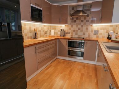 A kitchen with wooden countertops cabinets tiled backsplash and appliances at A Stone's Throw in Downderry