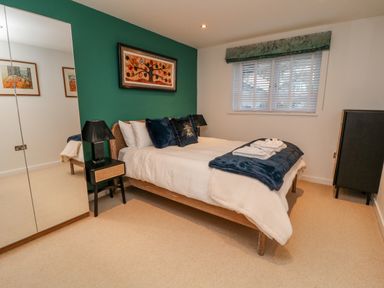A bedroom with a bed pillows and folded towels near a window with blinds at A Stone's Throw in Downderry