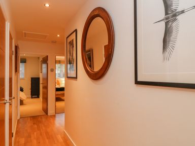 A hallway with wooden floor doors and framed artwork at A Stone's Throw in Downderry