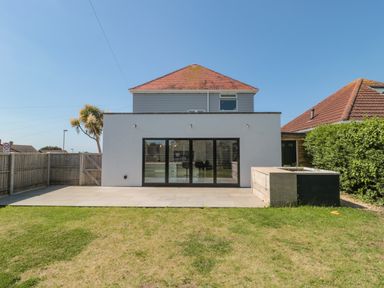 A backyard with a lawn patio and glass doors on a modern house at Fisherman's Rest in Wyke Regis