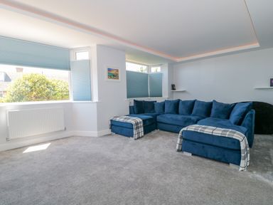 A living room with blue sectional sofa and gray carpet at Fisherman's Rest in Wyke Regis
