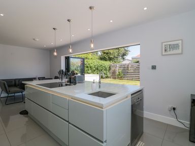 A kitchen with an island featuring a sink and cooktop and folding doors to a garden at Fisherman's Rest in Wyke Regis