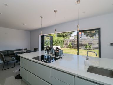 A modern kitchen with a white island countertop and seating area with chairs and a table at Fisherman's Rest in Wyke Regis