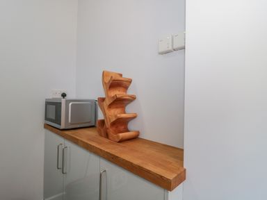 A kitchen countertop with a microwave and wooden wine rack at Fisherman's Rest in Wyke Regis