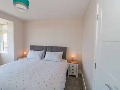 A bedroom with a double bed white bedding bedside tables and lamps at Fisherman's Rest in Wyke Regis