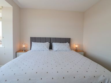 A bedroom with a large bed centered between two bedside tables each with a lamp at Fisherman's Rest in Wyke Regis