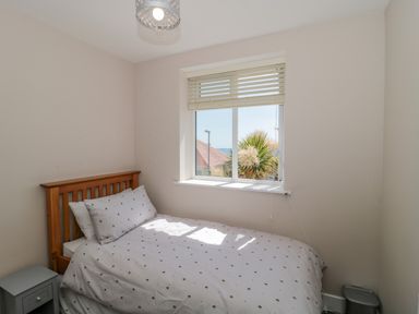 A bedroom with a wooden bed a window with blinds and a bedside table at Fisherman's Rest in Wyke Regis