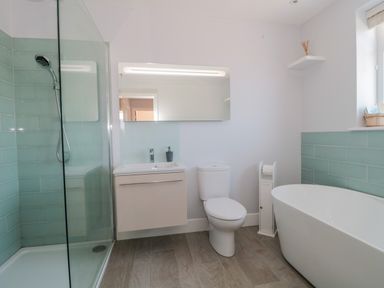 A bathroom with a shower area sink toilet freestanding bathtub and a small shelf at Fisherman's Rest in Wyke Regis