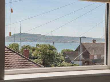 A view of rooftops trees water and hills seen through a window at Fisherman's Rest in Wyke Regis