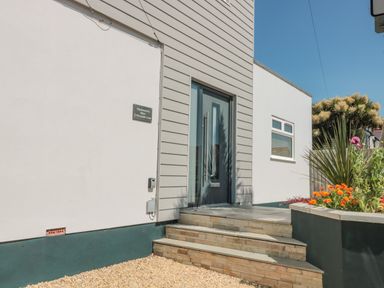 The front entrance of a house with tiled steps a modern door and a garden bed with flowers at Fisherman's Rest Wyke Regis