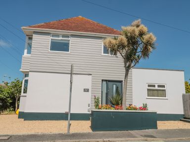 A two story house with a tree and flower bed in front at Fisherman's Rest in Wyke Regis