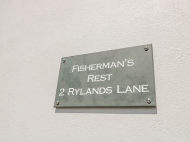 A stone plaque with the text Fisherman's Rest 2 Rylands Lane on a white exterior wall at Fisherman's Rest in Wyke Regis