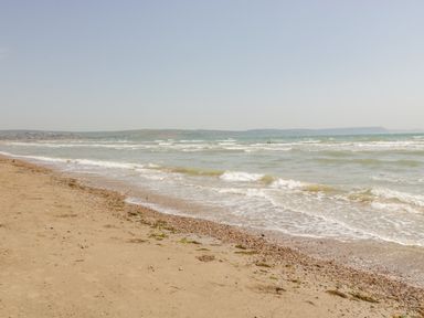 A sandy beach with small waves and a distant coastline at Fisherman's Rest in Wyke Regis
