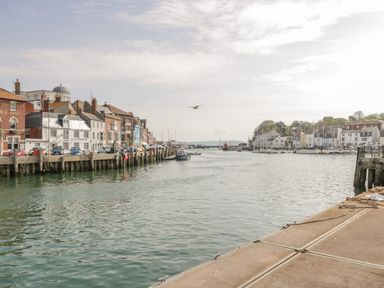 A harbor with boats docked along the water and buildings lining the shore at Fisherman's Rest in Wyke Regis