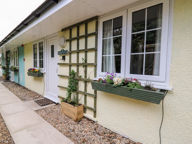 The exterior of a building with windows flower boxes a white door and a sign reading Primrose Cottage at Crossgates