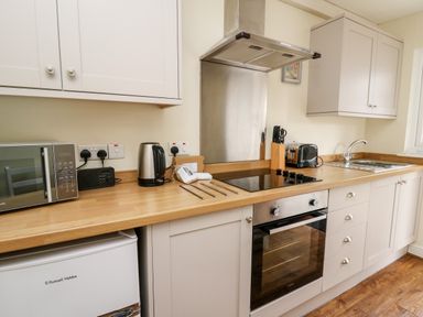 A kitchen with a microwave kettle toaster oven stove sink and cabinets at Primrose Cottage in Crossgates