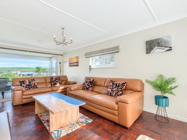 A living room with two brown leather sofas a wooden coffee table and a potted plant at Beach Haven in Polzeath