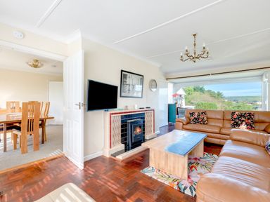 A living room with leather sofas and a coffee table near a window at Beach Haven in Polzeath