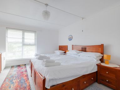 A bedroom with two wooden beds white bedding and a colorful rug at Beach Haven in Polzeath