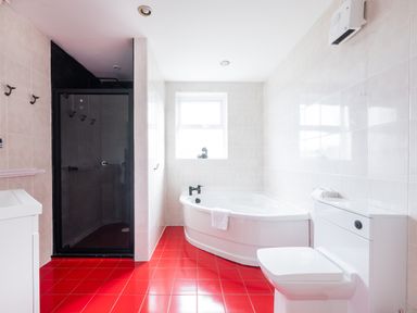 A bathroom with a bathtub a shower toilet and red tiled floor at Beach Haven in Polzeath