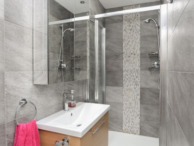 A bathroom with a shower area a sink with a faucet and a pink towel at Alltwen in Borth-y-Gest