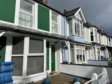 A row of terraced houses with bay windows and different colored facades including green and blue at Alltwen in Borth-y-Gest