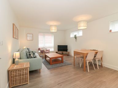 A living room with a sofa coffee table and dining table at Apartment 1 in Exmouth