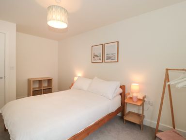 A bedroom with a bed bedside tables lamps artwork and a clothes rack at Apartment 1 in Exmouth