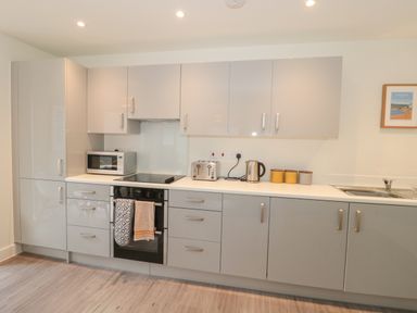 A kitchen with gray cabinets a microwave toaster and kettle at Apartment 9 in Exmouth
