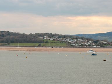 A coastal view with boats floating on water and houses on a hill in the background at Apartment 9 in Exmouth