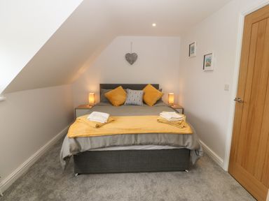 A bedroom with a double bed two bedside tables with lamps and a wooden door at Bryn Eglwys Bach in Penmynydd near Llanfairpwllgwyngyll