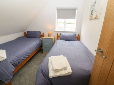 A bedroom with two single beds and a nightstand with a lamp at Bryn Eglwys Bach in Penmynydd near Llanfairpwllgwyngyll