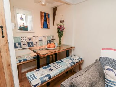 A dining nook with a wooden table and cushioned benches next to a gray sofa at Stonewall in Sandsend