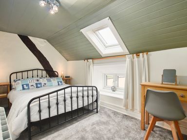 A bedroom with a black metal bed frame a wooden desk and chair and a skylight window at Stonewall in Sandsend