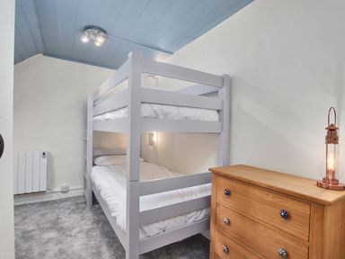 A bedroom with a bunk bed a wooden dresser and a lantern on top at Stonewall in Sandsend