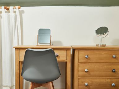 A wooden vanity and dresser with mirrors and a gray chair in a room at Stonewall in Sandsend