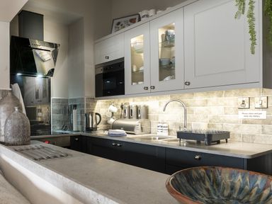 A kitchen with black and white cabinets a countertop with a kettle and sink at Harbour View - Flat 2 in Barmouth