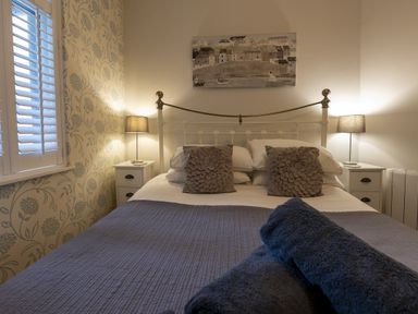 A bedroom with a double bed two bedside tables with lamps and folded towels at Harbour View - Flat 2 in Barmouth