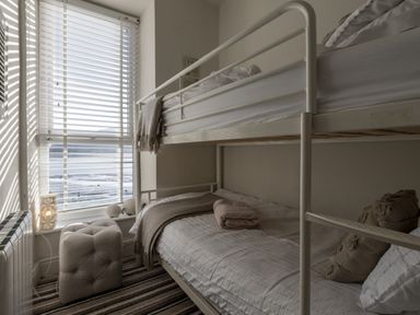 A bedroom with a bunk bed next to a window with blinds at Harbour View - Flat 2 in Barmouth