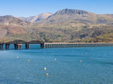 A body of water with a long train bridge and mountains in the background at Harbour View  Flat 2 in Barmouth