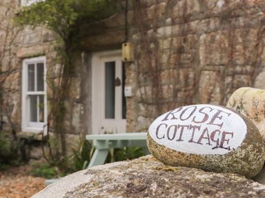 A stone with Rose Cottage written on it in front of a stone cottage with a white door and window at Rose Cottage Lower Bostraze near St Just