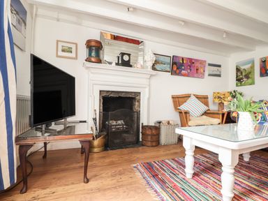 A living room with a fireplace television wicker chair and coffee table at Rose Cottage in Lower Bostraze near St Just