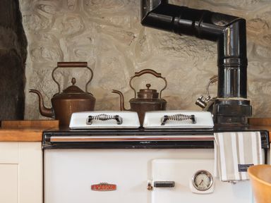 A kitchen stove with two kettles and a striped towel on a stove handle at Rose Cottage in Lower Bostraze near St Just