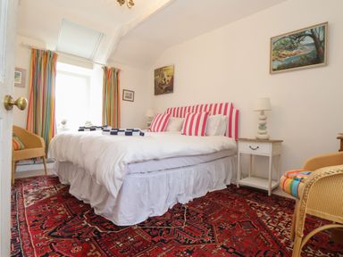A bedroom with a double bed with striped pillows and colorful curtains at Rose Cottage in Lower Bostraze near St Just